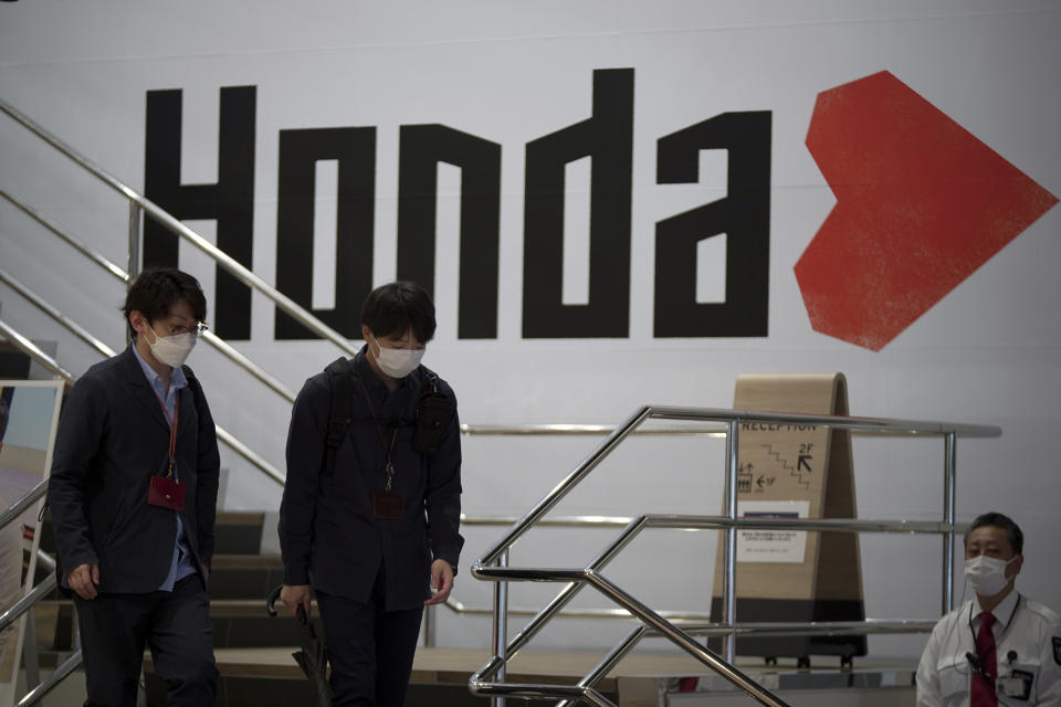 People walk near the logo of Honda Motor Company at a showroom Friday, May 13, 2022, in Tokyo. Honda’s fiscal fourth quarter profit slipped to almost half of what the Japanese automaker earned the previous year amid headwinds of supply shortages and rising raw material costs. (AP Photo/Eugene Hoshiko)