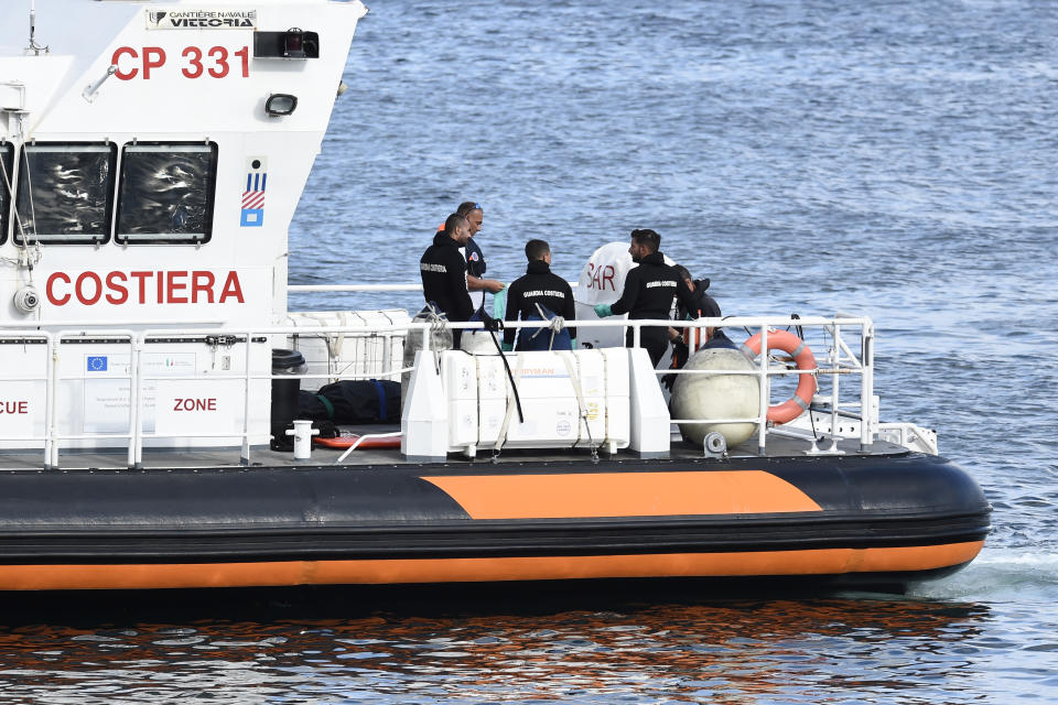 Italian Coast Guard officials bring ashore in a bag the body of one of the victims of the UK flag vessel Bayesian, Wednesday, Aug. 21, 2024. The sail yacht was hit by a violent sudden storm and sunk early Monday, while at anchor off the Sicilian village of Porticello near Palermo, in southern Italy. (AP Photo/Salvatore Cavalli)