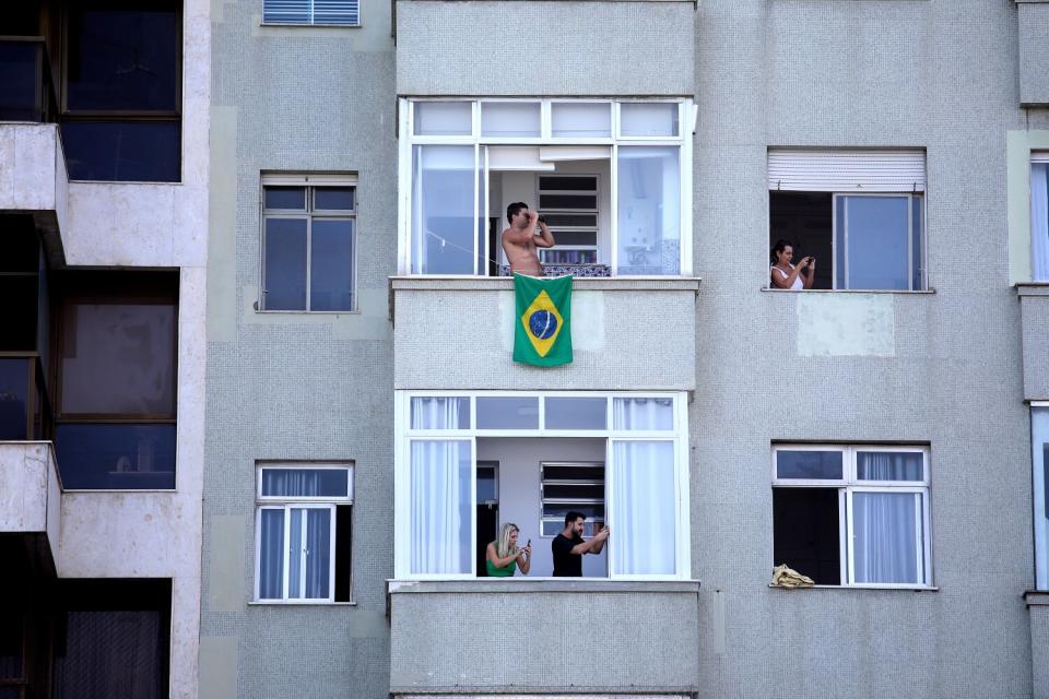 People peer out of their windows during a celebration.