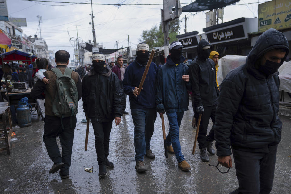 Masked men from The Popular Committee for Protection patrol the streets armed with batons and guns in Rafah, Gaza Strip, Thursday, March 7, 2024. The committee are a new youth-based group that monitors prices and law and order, across markets in war-ravaged Gaza. (AP Photo/Fatima Shbair)