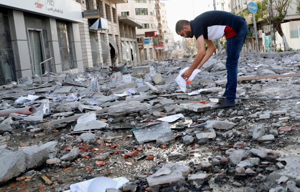 A man inspects the rubble of destroyed commercial building and health care clinic after an Israeli airstrike in Gaza City on May 17, 2021.