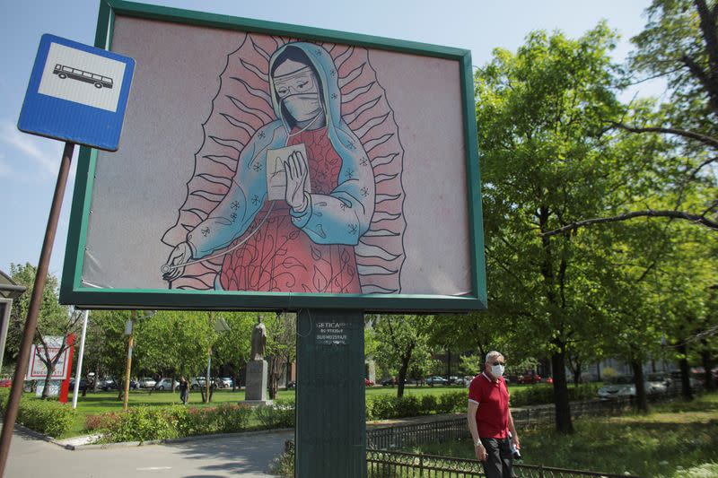 An outdoor poster shows a doctor depicted in a style similar to Latin American religious paintings