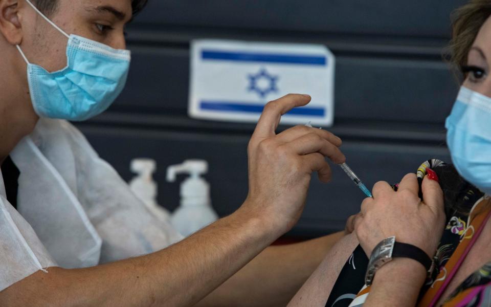 An Israeli receives a coronavirus vaccine from medical staff at a COVID-19 vaccination center in Tel Aviv, Israel - Sebastian Scheiner /AP