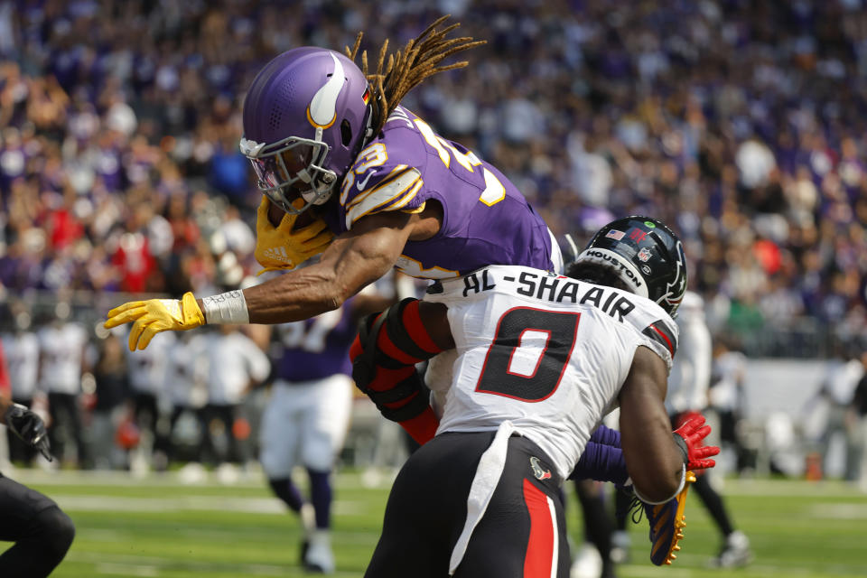 Minnesota Vikings running back Aaron Jones (33) scores on an 8-yard touchdown reception over Houston Texans linebacker Azeez Al-Shaair (0) during the first half of an NFL football game, Sunday, Sept. 22, 2024, in Minneapolis. (AP Photo/Bruce Kluckhohn)