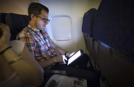 A passenger uses a wireless tablet on an American Airlines airplane, which is equipped with Gogo Inflight Internet service, enroute from Miami to New York, in this file picture taken December 10, 2013. REUTERS/Carlo Allegri/Files