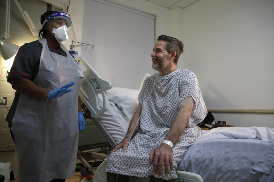 Felicia Kwaku, Associate Director of Nursing, with recovering COVID-19 patient Justin Fleming on the Cotton ward at King's College Hospital in London, Wednesday, Jan. 27, 2021. Fleming is one of more than 37,000 coronavirus patients being treated now in Britain's hospitals, almost double the number of the spring surge. King's College Hospital, which sits in a diverse, densely populated area of south London, had almost 800 COVID-19 patients earlier this winter. (AP Photo/Kirsty Wigglesworth, Pool)