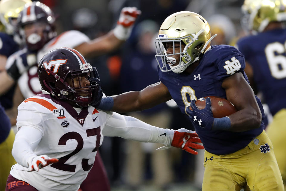 FILE - In this Nov. 2, 2019, file photo, Notre Dame running back Jafar Armstrong (8) stiff arms Virginia Tech linebacker Rayshard Ashby (23) during the second half of an NCAA college football game in South Bend, Ind. The Atlantic Coast Conference and Notre Dame are considering whether the Fighting Irish will give up their treasured football independence for the 2020 season play as a member of the league. (AP Photo/Carlos Osorio, File)