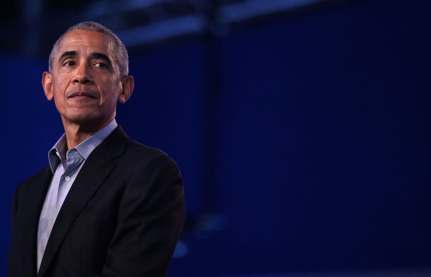 A man wearing a black suit and a blue button-up shirt