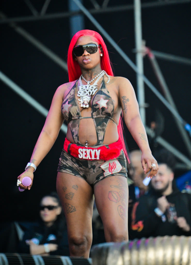 Sexyy Red performing in a star-patterned outfit with "SEXY" on shorts, accessorized with chain necklaces