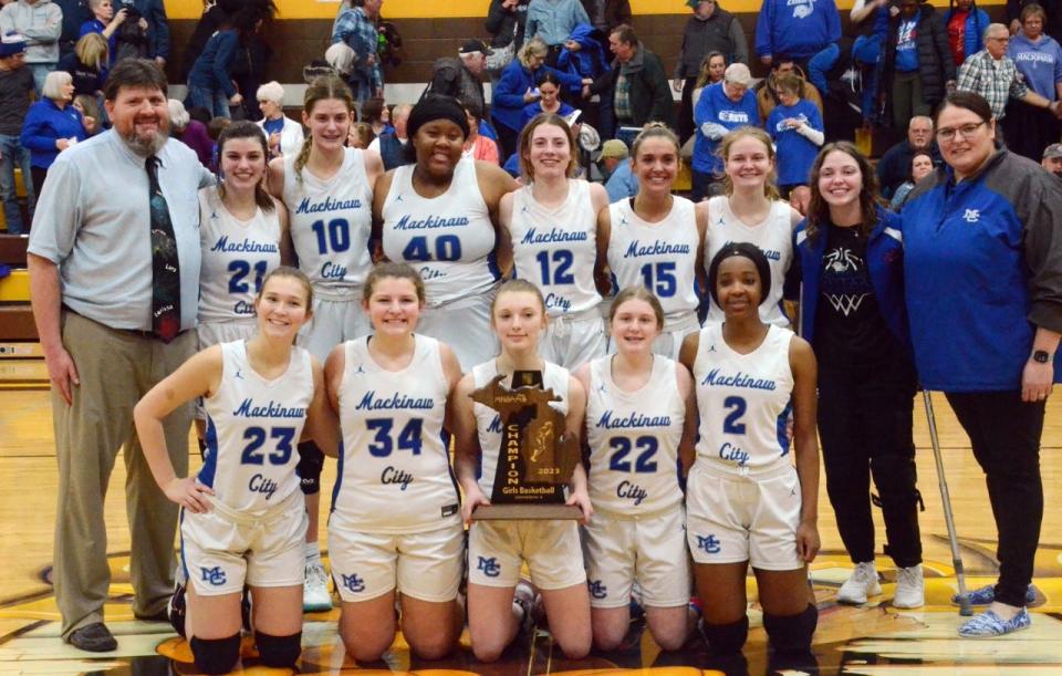 The Mackinaw City girls' basketball team shows off its first-ever regional championship trophy in the Pellston High School gym Thursday. Team members include (bottom, from left) Abby Brown, Alaina Brown, Rian Esper, Kenzlie Currie, Kerry-Ann Ming, (back) head coach Jake Huffman, Julia Sullivan, Madison Smith, Carla Blake, Larissa Huffman, Marlie Postula, Gracie Beauchamp, Jersey Beauchamp and assistant coach Amanda Munger.