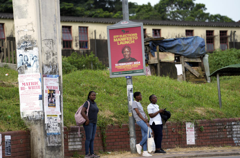 People wait for public transport underneath an election campaign poster with a portrait of Economic Freedom Fighters leader, Julius Malema in the Umlazi township in KwaZulu Natal province, South Africa, Friday, Feb. 9. 2024. Economic Freedom Fighters party will launch its election campaign manifesto on Saturday Feb. 10. The province is set to be the stage for political contestation for the hotly contested South African elections later this year. (AP Photo/Tsvangirayi Mukwazhi)