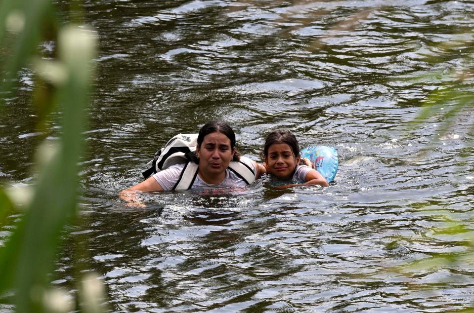 A migrant woman and her daughter swim back to Mexico after reaching the US bank of theRio Grande  and being stopped by members of the US National Guard in Matamoros, state of Tamaulipas, Mexico, on May 10, 2023.