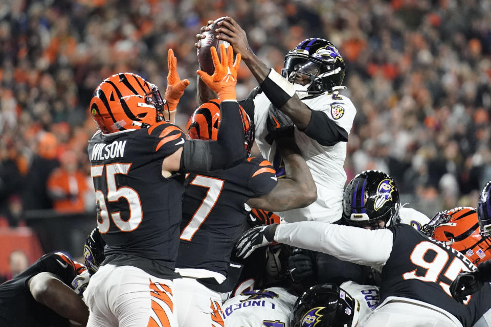 Baltimore Ravens quarterback Tyler Huntley, right, fumbles the ball as it is knocked away by Cincinnati Bengals linebacker Logan Wilson (55) in the second half of an NFL wild-card playoff football game in Cincinnati, Sunday, Jan. 15, 2023. The Bengals' Sam Hubbard recovered the fumble and ran it back for a touchdown. (AP Photo/Joshua A. Bickel)