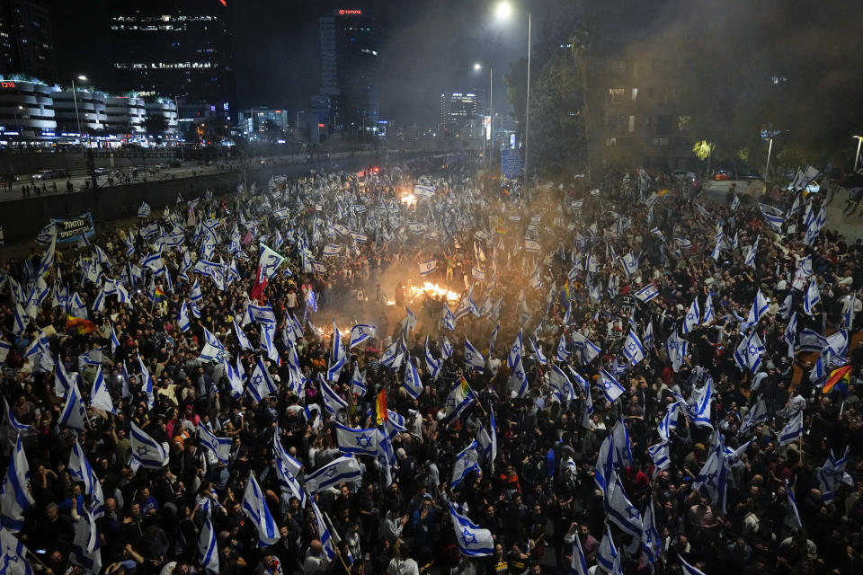 Israelis opposed to Prime Minister Benjamin Netanyahu's judicial overhaul plan set up bonfires and block a highway during a protest moments after the Israeli leader fired his defense minister, in Tel Aviv, Israel, Sunday, March 26, 2023. Defense Minister Yoav Gallant had called on Netanyahu to freeze the plan, citing deep divisions in the country and turmoil in the military. (AP Photo/Ohad Zwigenberg)