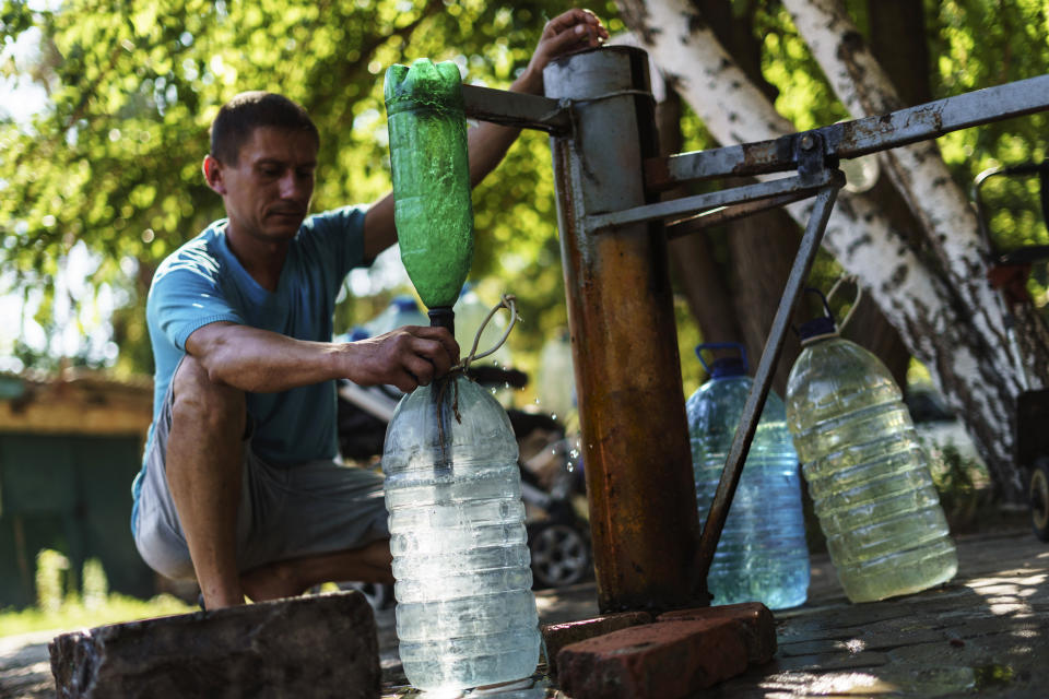 A resident fills up water bottles at a well in Sloviansk, Donetsk region, eastern Ukraine, Saturday, Aug. 6, 2022. The city has no running water as artillery and missile strikes have downed power lines and punched through water pipes. (AP Photo/David Goldman)