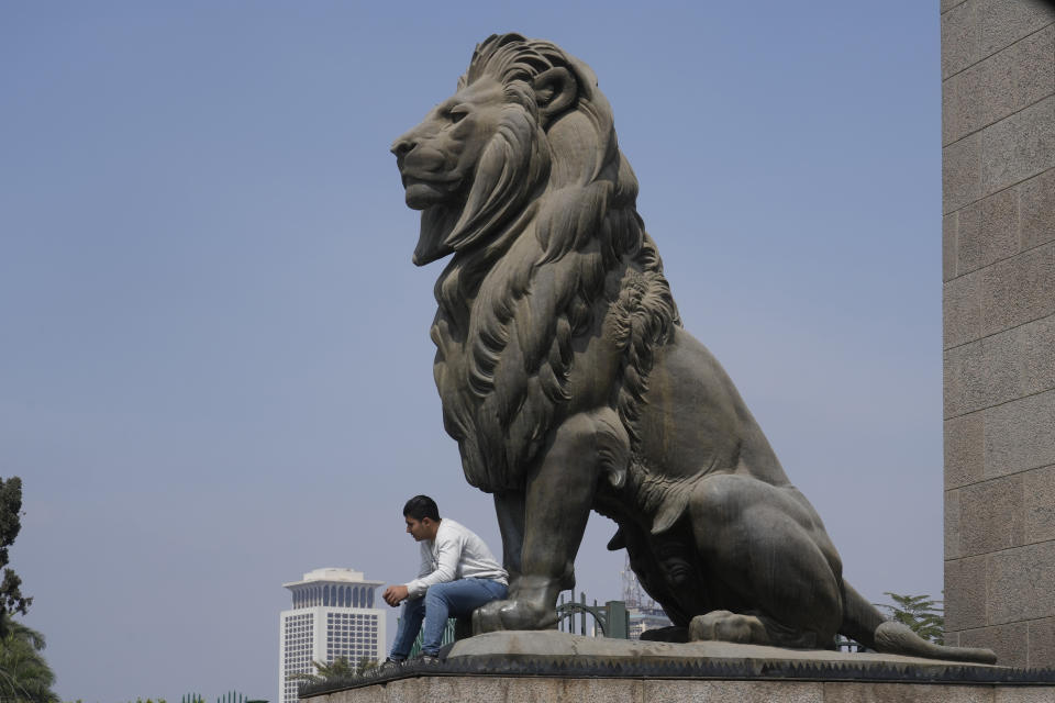 A man sits under an ancient bronze lion of Qasr El Nil Bridge in Cairo, Egypt, Tuesday, March 21, 2023. Egypt is embarking on a privatization push to help its cash-strapped government, after pressure from the International Monetary Fund. The new policy is supposed to be a serious departure for the Egyptian state, which has long maintained a tight grip over sectors of the economy. (AP Photo/Amr Nabil)