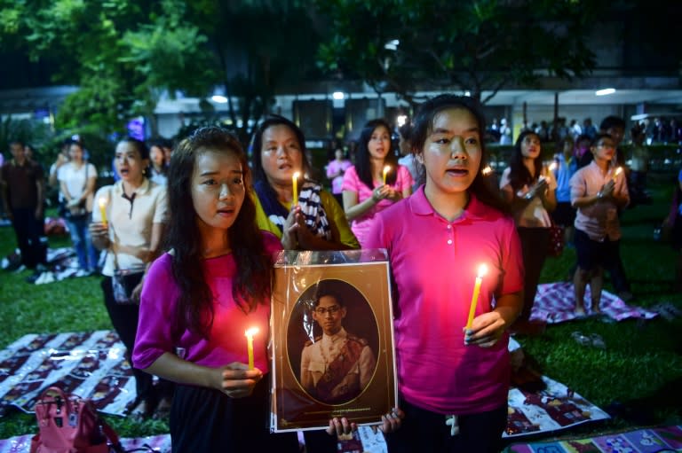 People hold a photo of Thailand's King Bhumibol Adulyadej as they react to his death on October 13, 2016 at Siriraj Hospital in Bangkok