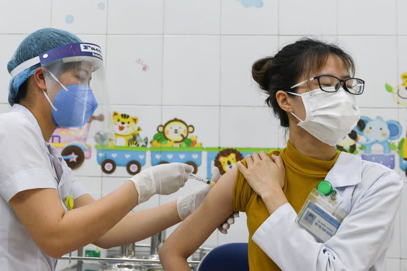 FILE PHOTO: A woman receives a vaccine as Vietnam starts its official rollout of AstraZeneca's COVID-19 vaccine, in Hai Duong