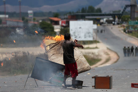 A man throws a burning mattress, at the border with Venezuela, seen from in Pacaraima, Brazil February 24, 2019. REUTERS/Ricardo Moraes