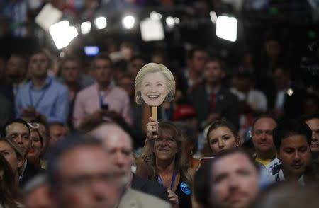 A delegate holds up a placard with an image of Democratic U.S. presidential nominee Hillary Clinton as her husban, former President Bill Clinton, speaks during the second night at the Democratic National Convention in Philadelphia, Pennsylvania, U.S. July 26, 2016. REUTERS/Carlos Barria