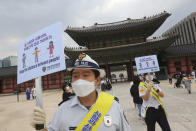 South Korean tourist police officers wearing face masks hold up social distancing signs at the Gyeongbok Palace in Seoul, South Korea, Wednesday, Sept. 30, 2020. Officials have called for citizen vigilance ahead of the Chuseok harvest festival that began Wednesday and continues through the weekend. (AP Photo/Ahn Young-joon)