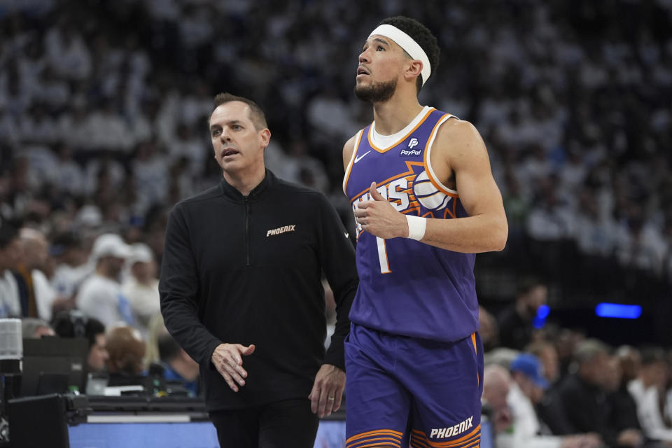 Phoenix Suns head coach Frank Vogel and guard Devin Booker (1) walk toward the bench during the first half of Game 1 of an NBA basketball first-round playoff series against the Minnesota Timberwolves, Saturday, April 20, 2024, in Minneapolis. (AP Photo/Abbie Parr)