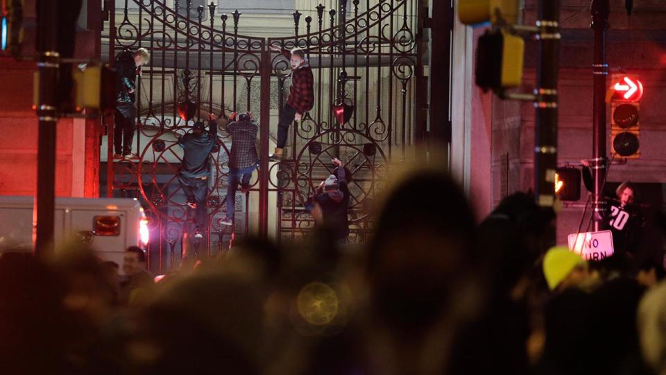 <p>Fans climb the City Hall gates.</p>