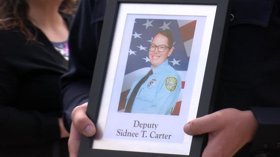 A law enforcement officer holds the picture of Deputy Sidnee Carter during a memorial service in Wichita on May 15, 2024. (KSN News Photo)