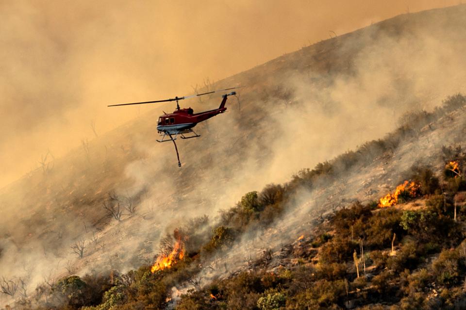 A helicopter prepares to drop water on the Lake Fire burning in the Angeles National Forest north of Santa Clarita, Calif., on Thursday/