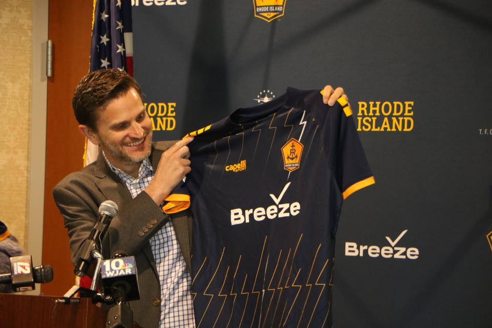 Tom Doxey, president of Breeze Airways, reveals the uniforms that will be worn by RIFC, the state's new professional soccer team, at Monday's announcement.