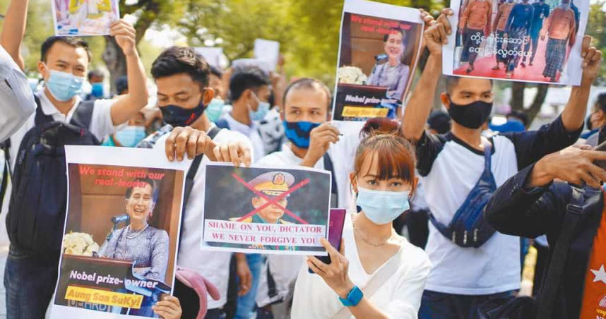 居住在泰國的緬甸公民3日聚集在曼谷聯合國機構外，他們手舉翁山蘇姬以及武裝部隊總司令敏昂萊的照片，其中敏昂萊的臉上被畫上紅色大叉，以此表示對翁山的支持。（路透）