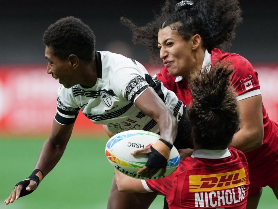 Fiji's Reapi Ulunisau, left, is tackled by Canada's Breanne Nicholas and Olivia De Couvreur during Fiji's 22-17 win in their fifth-place match on Sunday at the HSBC Canada Sevens event at BC Place in Vancouver. (Darryl Dyck/The Canadian Press - image credit)