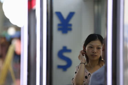 A woman stands outside at a foreign exchange store in Shanghai, China, August 14, 2015. REUTERS/Aly Song