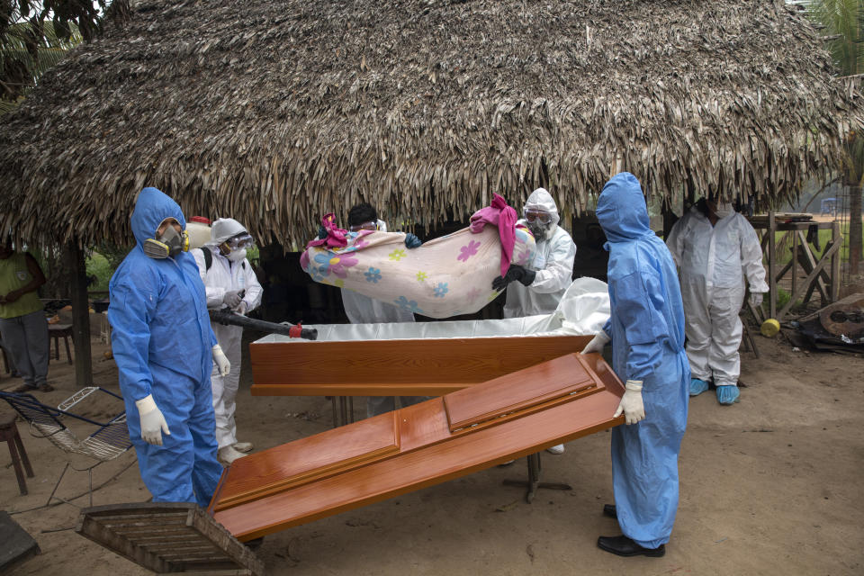 Un equipo gubernamental retira el cuerpo de Manuela Chávez, quien murió por síntomas relacionados con el coronavirus a los 88 años, de su casa y lo introduce en un ataúd, en la comunidad indígena Shipibo en Pucallpa, en la región peruana de Ucayali, el 31 de agosto de 2020. En el apogeo del brote en mayo y junio, alrededor de 15 personas fallecían a diario, dijo Juan Carlos Salas, director de la agencia de salud de la región de Ucayali. (AP Foto/Rodrigo Abd)