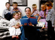 This undated photo provided by Robert Krause shows his daughter, Sasha Krause, center, reading a book to children in Farmington, New Mexico. Krause was killed in early 2019. Air Force Airman Mark Gooch was found guilty of first-degree murder and will be sentenced Jan. 19, 2022. (Family Photo/Robert Krause via AP)