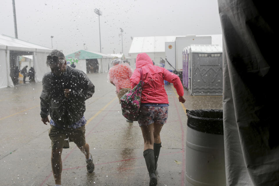 Festival-goers run from the downpour at the WWOZ Jazz tent at the New Orleans Jazz & Heritage Festival New Orleans, Thursday, April 25, 2019. The opening was delayed by heavy rain. (AP Photo/Doug Parker}