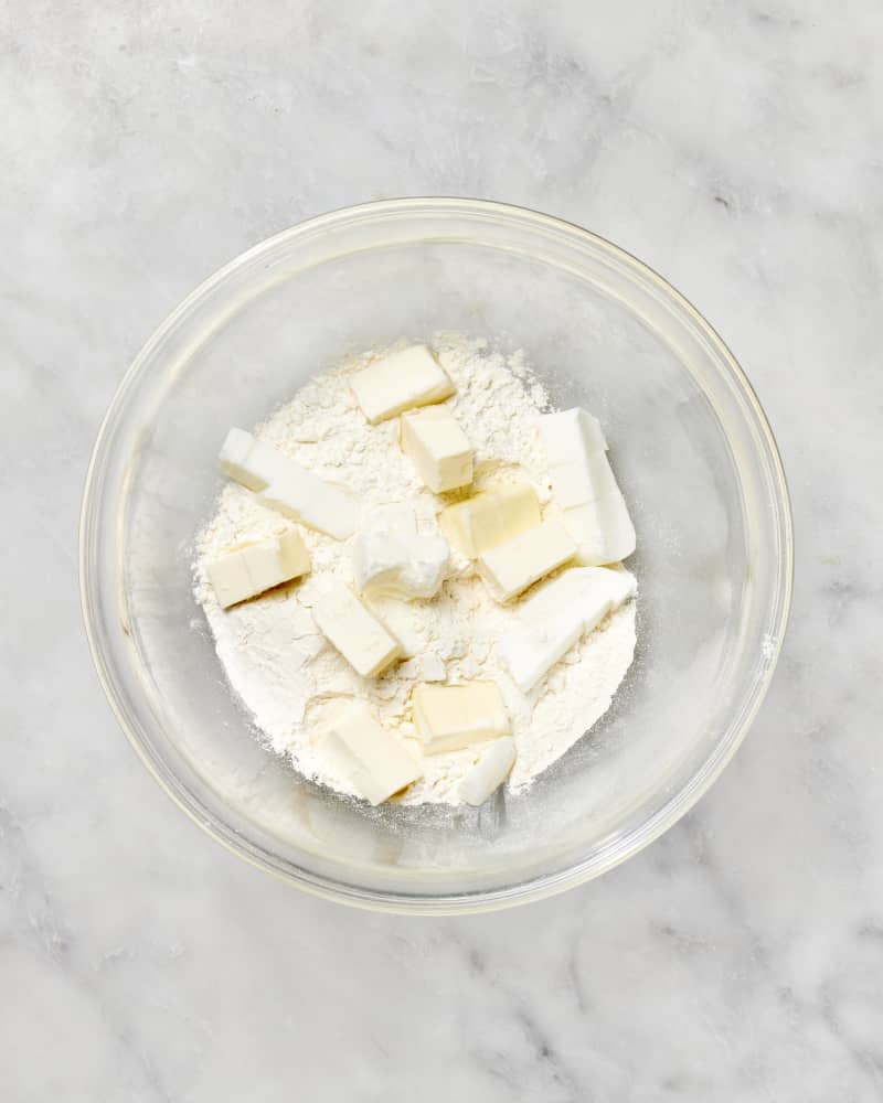 A bowl with flour and cubes of butter and shortening to make a pie crust seen from above.