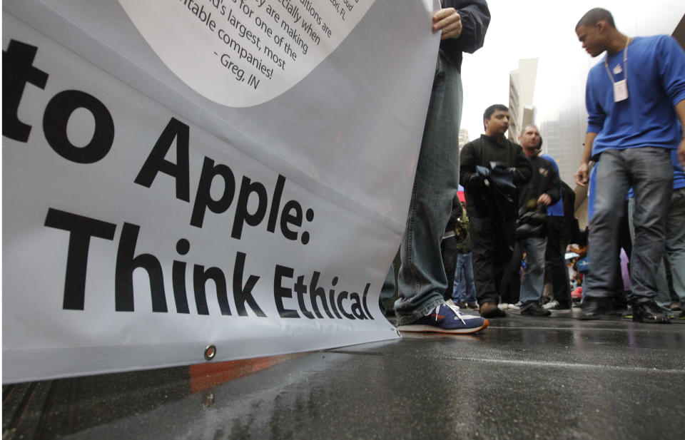 Change.org demonstrators displaya sign outside an Apple store as a customer walks in on the first day of the launch of the new iPad, in San Francisco, Friday, March 16, 2012. The demonstrators are asking Apple to stop worker abuse in factories in China during the release of the new iPad. (AP Photo/Paul Sakuma)