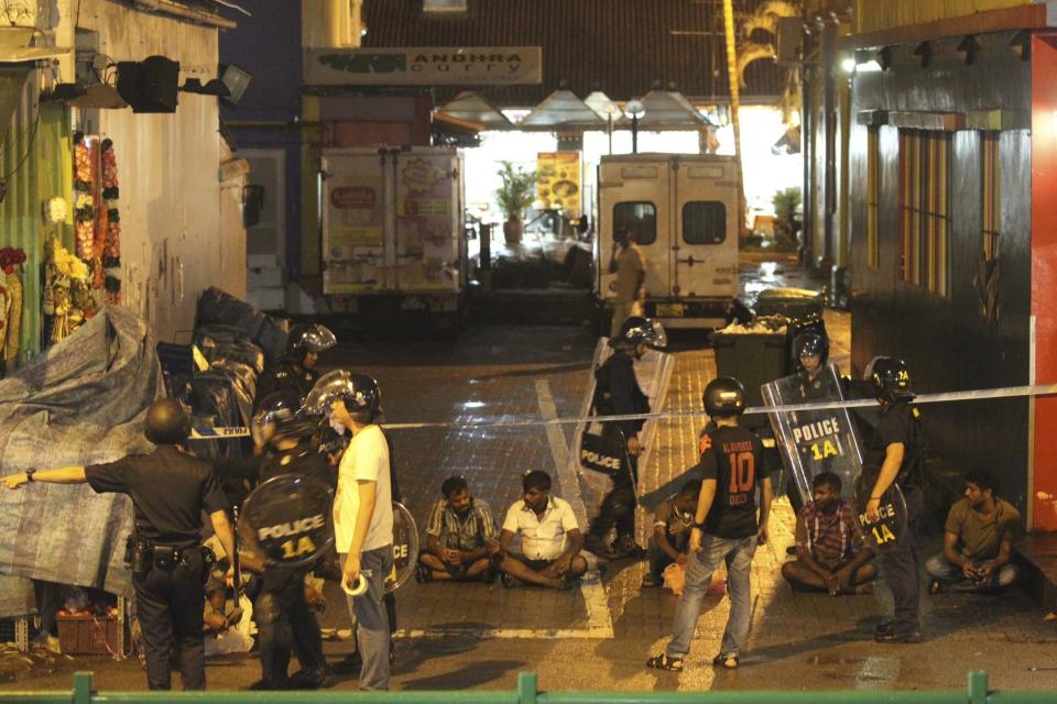 Police detain men following a riot in Singapore's Little India district, late December 8, 2013. Local media said a mob of about 400 set fire to an ambulance and police cars during the riot on Sunday, which started after a bus knocked down a pedestrian. REUTERS/Dennis Thong/Lianhe Zaobao (SINGAPORE - Tags: CIVIL UNREST) ATTENTION EDITORS - THIS IMAGE HAS BEEN SUPPLIED BY A THIRD PARTY. IT IS DISTRIBUTED, EXACTLY AS RECEIVED BY REUTERS, AS A SERVICE TO CLIENTS. NO SALES. NO ARCHIVES. FOR EDITORIAL USE ONLY. NOT FOR SALE FOR MARKETING OR ADVERTISING CAMPAIGNS. SINGAPORE OUT. NO COMMERCIAL OR EDITORIAL SALES IN SINGAPORE