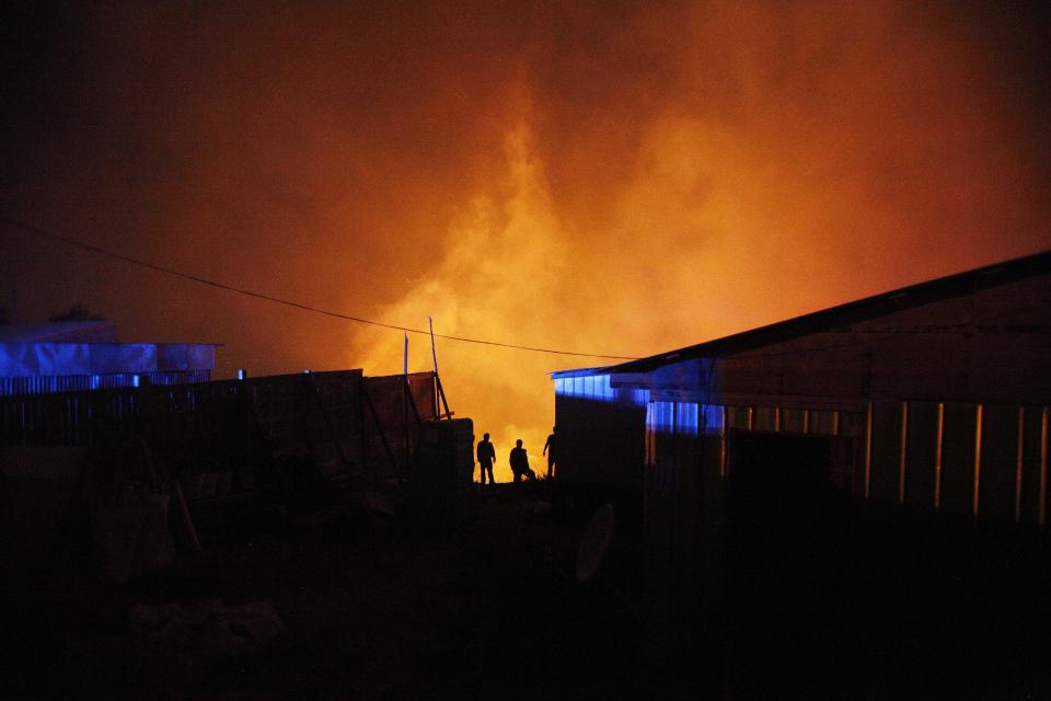 A group of firefighters stand next to burning homes as a forest fire rages towards urban areas in the city of Valparaiso, Chile, Sunday April 13, 2014. . Authorities say the fires have destroyed hundreds of homes, forced the evacuation of thousands and claimed the lives of at least seven people. ( AP Photo/ Luis Hidalgo)