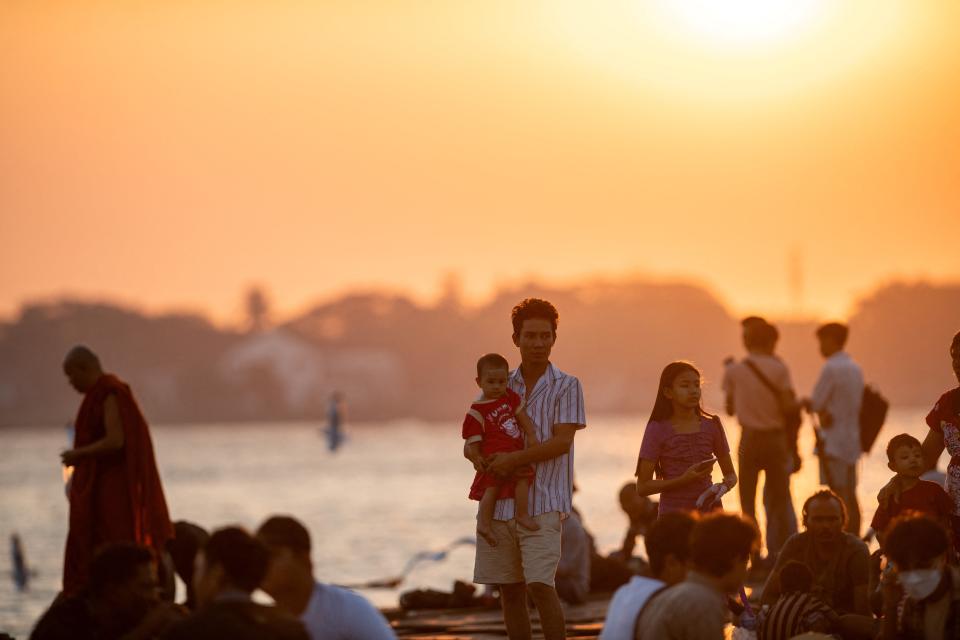 People gather to observe the last sunset of the year at the Botahtaung jetty on Yangon River in Yangon (AFP via Getty Images)