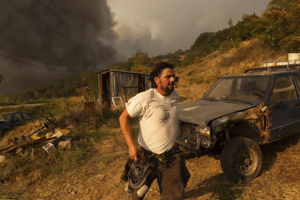 A man walks away as flames burn a forest during wildfires in the village of Sykorrahi, near Alexandroupolis town, in the northeastern Evros region, Greece, Wednesday, Aug. 23, 2023. Advancing flames are devouring forests and homes in Greece as wildfires that have killed 20 people are raging. (AP Photo/Achilleas Chiras)