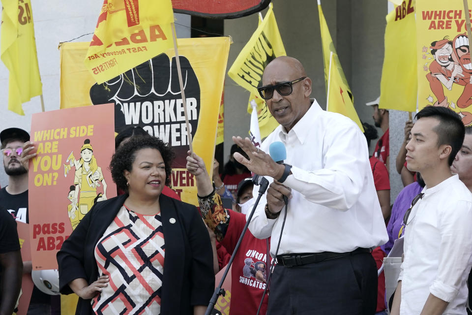 Assemblyman Chris Holden, D-Los Angeles, center, speaks about his bill to provide increased power to fast-food workers during a rally in Sacramento, Calif., Tuesday, Aug. 16, 2022. If approved by lawmakers and signed by the governor, California's more than half-million fast food workers would get increased power and protections under Holden's first-in-the-nation measure. Holden was flanked by Democratic Assembly members Mia Bonta, of Oakland, left and Alex Lee of San Francisco, right. (AP Photo/Rich Pedroncelli)