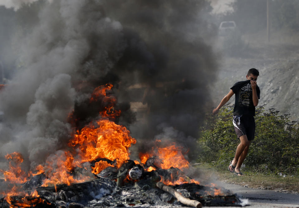 A Kosovo Albanian runs past a fire burning at a roadblock in Vojtesh, Kosovo, Sunday, Sept. 9, 2018. Kosovo Albanians burned tires and blocked roads with wooden logs, trucks and heavy machinery on a planned route by Serbia's President Aleksandar Vucic who was trying to reach the village of Banje while visiting Serbs in the former Serbian province. (AP Photo/Visar Kryeziu)