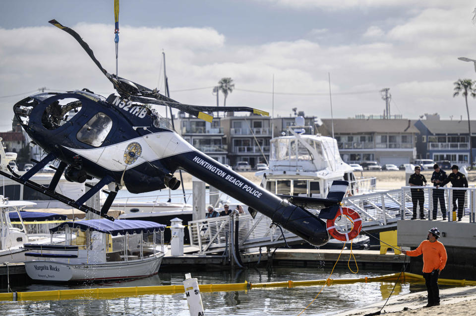 A Huntington Beach Police helicopter is lifted out of the water in Newport Beach, Calif., Sunday, Feb. 20, 2022. Authorities were investigating the cause of a police helicopter crash along the Southern California coast that killed Huntington Beach Officer Nicholas Vella, a 14-year veteran of the force, and sent another officer to the hospital with critical injuries. (Mindy Schauer/The Orange County Register via AP)