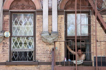 A man peers from a Lower East Side apartment window as a heatwave continued to affect the region in Manhattan, New York City