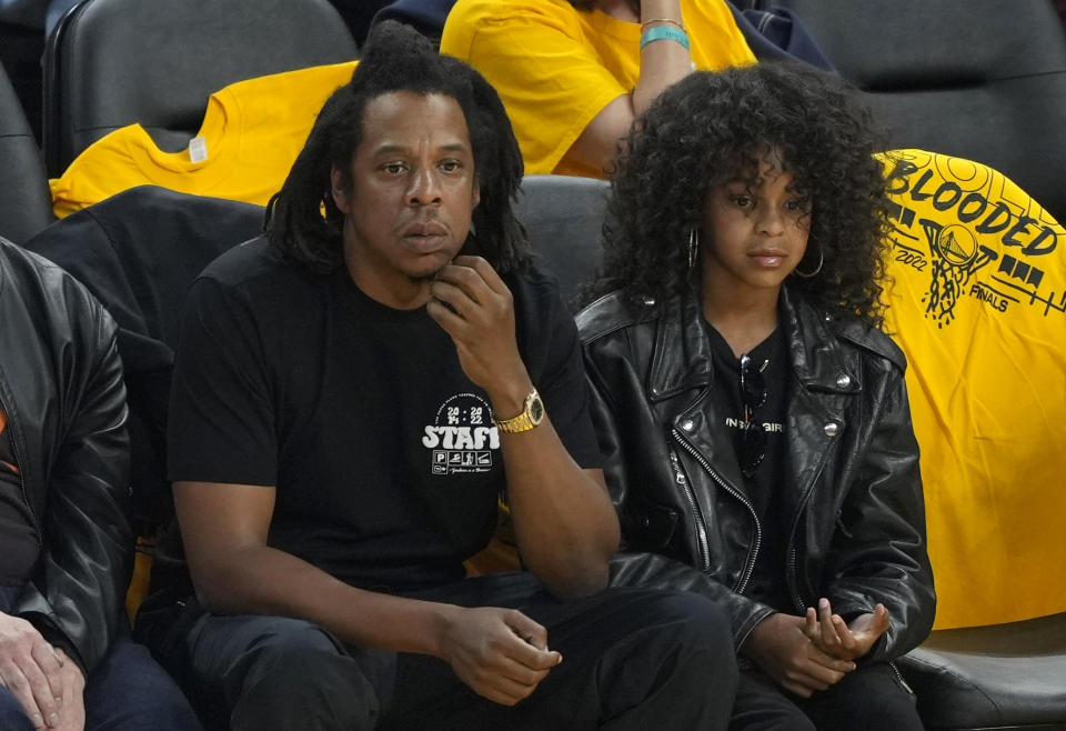 Hov and Blue dressed in all black sitting curtsied at a Golden State Warriors game.