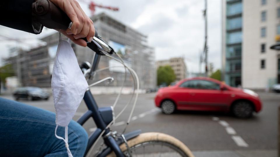 Eine Frau fährt mit Fahrrad und Mundschutz durch Stuttgart.