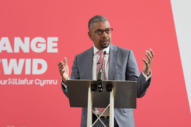 Vaughan Gething stands with his arms in the air at a Labour party campaign event