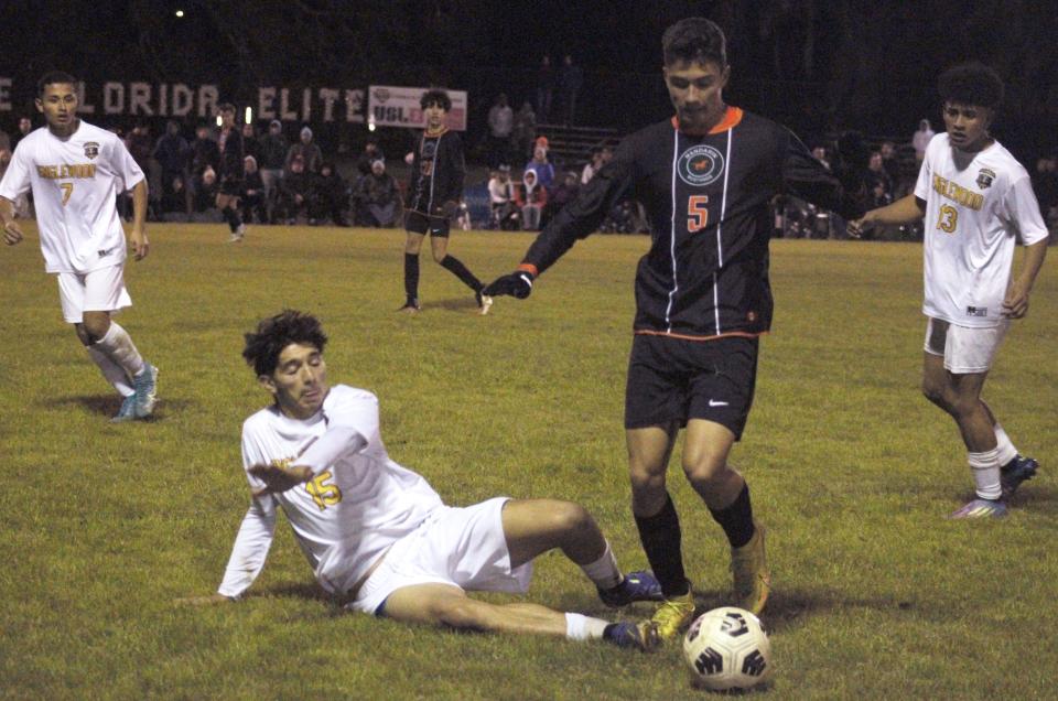 Mandarin midfielder Zack Kertesz (5) tries to sidestep the sliding tackle of Englewood midfielder Fredy Escobar-Lopez (15) during Friday's Gateway Conference boys soccer final.